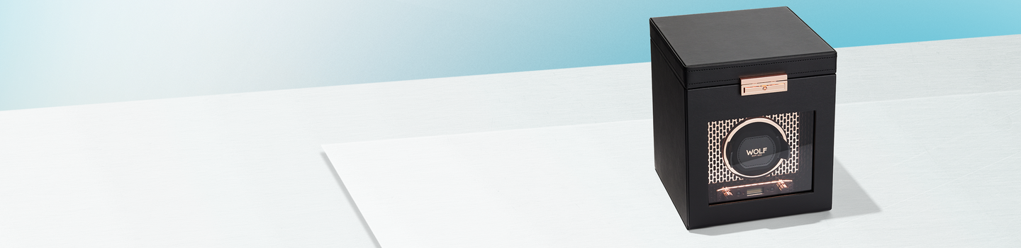 Remontoir Wolf axis en cuivre sur fond bleu clair.